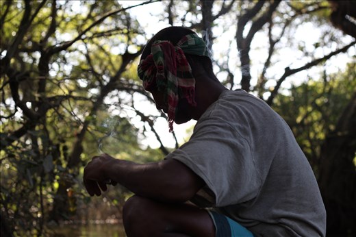 This man takes a break from rowing by smoking a cigarette and singing folk songs