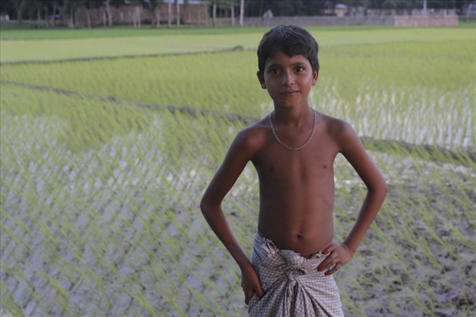 Boy in front of the rice fields, showing off to his friends (behind the camera)
