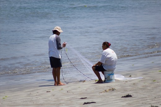 A man tries on shore fishing while his wife waits.
