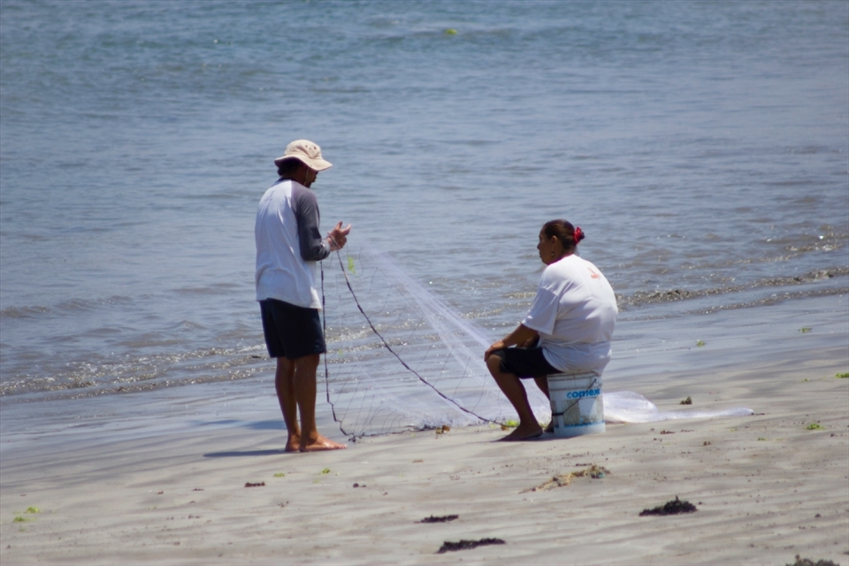 A man tries on shore fishing while his wife waits.