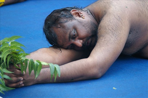Hindu man having breather during ritual rolling for the Thimithi festival, the practice of rolling around the  sri Mariamman  temple can last all day for the men .The neem leaves are to ward off evil