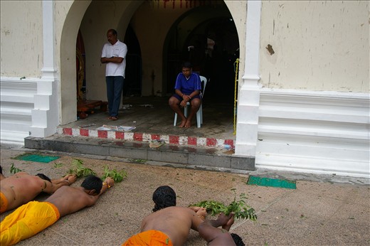 Onlookingers watch rollers past temple doors during Thimithi festival , Juvenile males don’t roll around the temple but participate by watching the spectacle of endurance .The neem leaves are to ward off evil