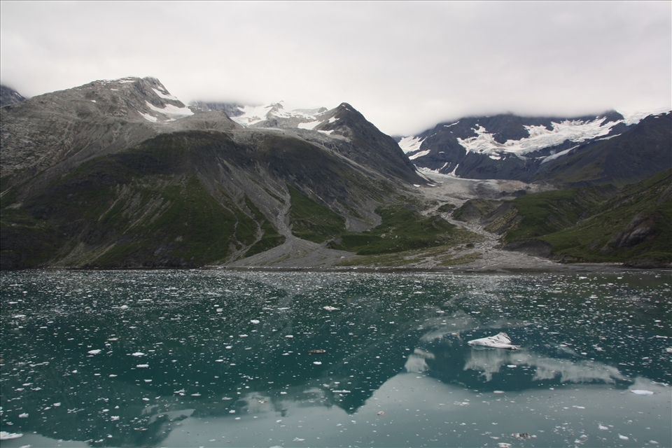 Glacier remains & scars surround the inlet, while slit colours the water. 