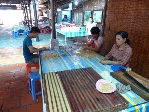 Coconut candy cooled in trough forms, chopped into small squares, wrapped and packaged by hand for retail.
