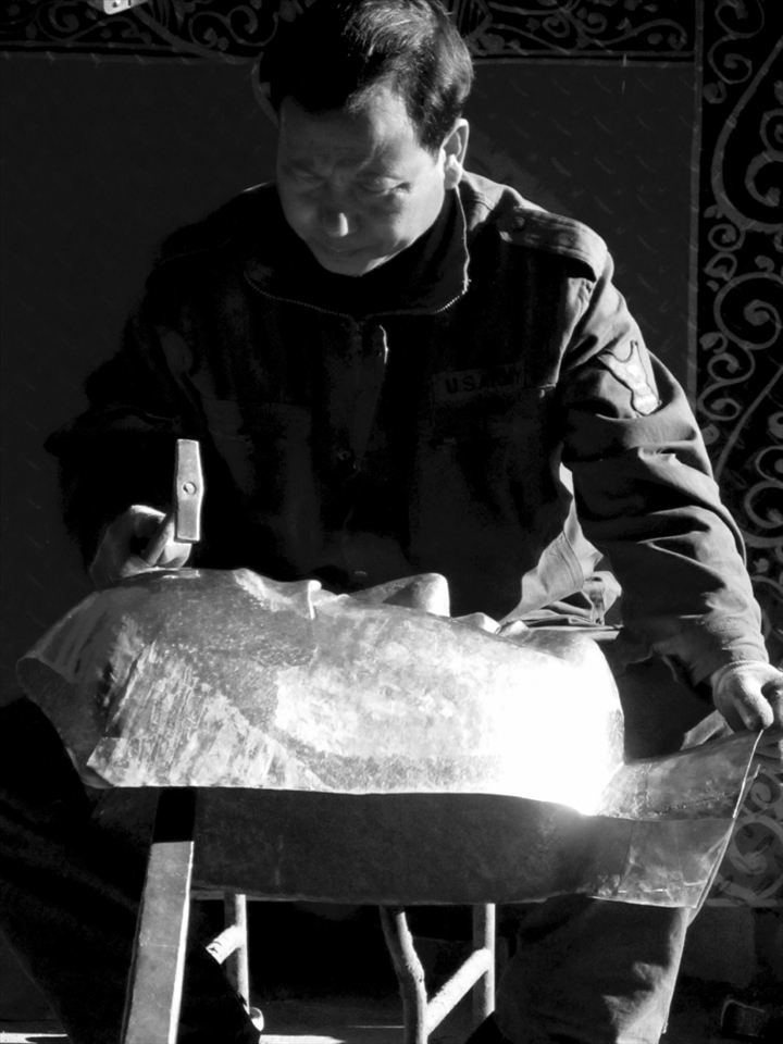 The metal worker:
This man works downstairs from the painter. He spends his days in the largely outdoor workshop creating three dimensional mandalas (stupa) and decorations for monasteries. He is a highly skilled blacksmith, and one of the few remaining who still work in the traditional fashion after the introduction of the Chinese into Tibet.
