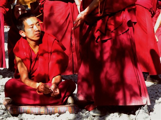 The monk:
This young boy is one of several hundred living in Sera monastery on the outskirts of Lhasa. Every day the boys and men congregate in this courtyard to debate topics ranging  from meditation to the politics of foreign countries and beyond. Sera is well known for this practise which provides forward thinking and vast knowledge to the monks of this living, evolving religion. This boy sits, playing the role of the opposition in the debate, resisting the cracking prayer beads and fervent movements of his standing 'positive' partner. 