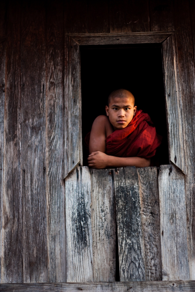 After the feasting, the child parading and buckets of tea drinking, sunset brings the villages to the local monastery. Built with local teak wood, it's brown façade is fading, but beautifully and elegantly. The inside creeks with every footstep of my heavy trekking boots. But the barefoot monks  pass without a sound. As gentle as their faces, they follow me to an upstairs window. Below sees a parade of novices, local children in their best jewels, on hired horses, and surrounded by uncles and cousins playing sheep skin drums. The spectacle seems too brash for the simplicity of the Buddha's way, but it's only for a day. Tomorrow the children will learn serenity, and how to walk with silent feet through the teak monasteries.
