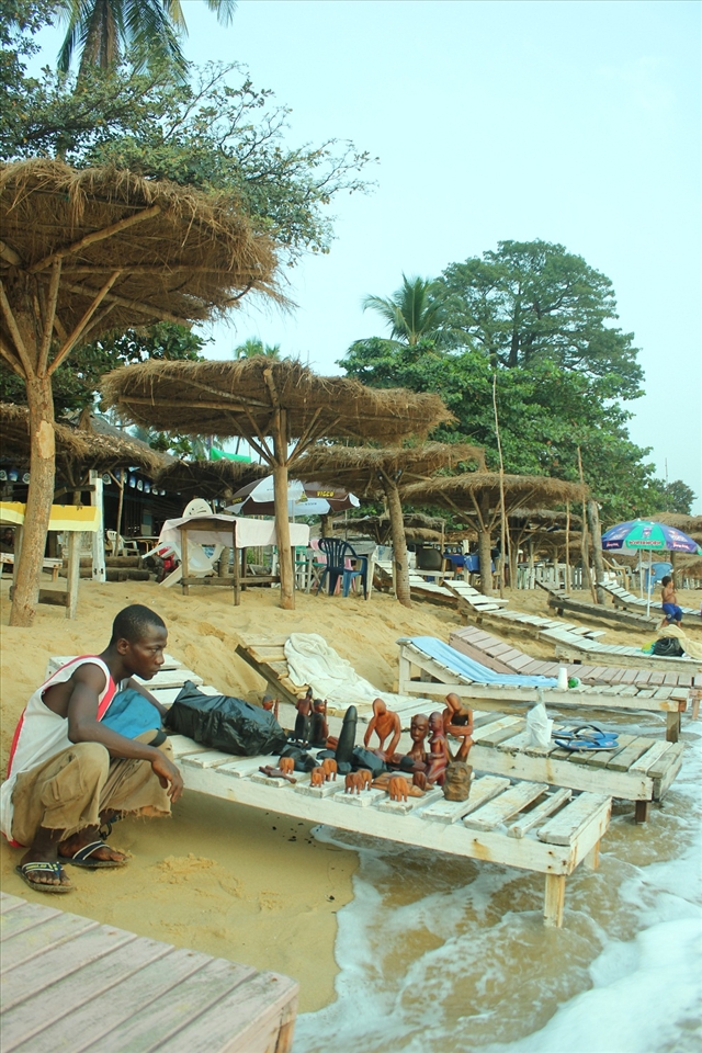 Alfa Kargbo jumps to save his crafts from waves that now reach the bars.