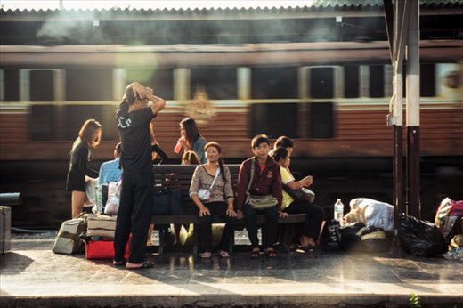 A family at the waiting bench, next to the rail track when a train comes through