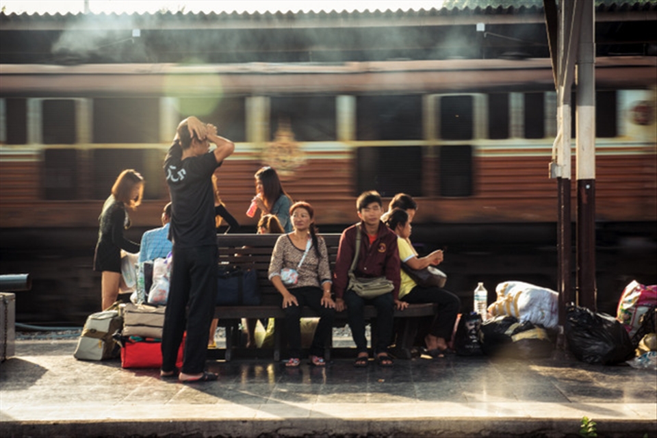 A family at the waiting bench, next to the rail track when a train comes through