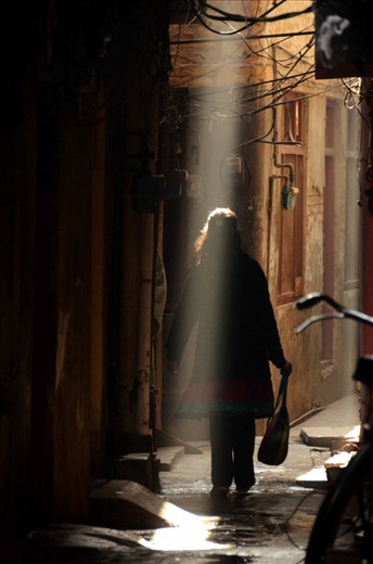 Streets of Lahore are so full of surprises, somewhere a maze of dark narrow alleys where light rarely reaches to vast courtyard of Mughal Era Mosques. The streets are alive with the voices of street vendors, laughing children, chattering elders, merry voices of girls behind the curtained dingy quarters and women bickering with vendors.

I found this quite and serene moment among the jumble of voices and activities. A women passes by a street when a narrow shaft of light illuminates her