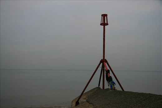Here is a photo looking out at the gloomy grey sea with a wave bracer and red tower on the far right on the screen.