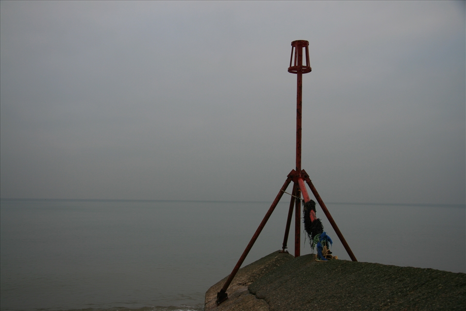 Here is a photo looking out at the gloomy grey sea with a wave bracer and red tower on the far right on the screen.