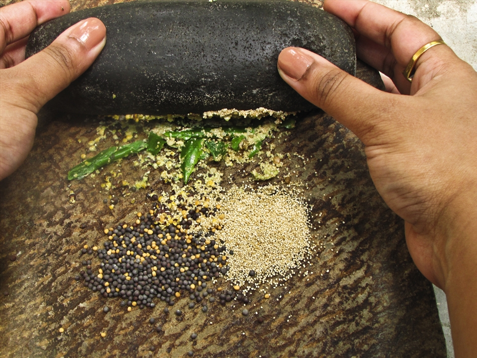 Grinding the ingredients on a traditional grinding stone, or 'Shil Nora'.