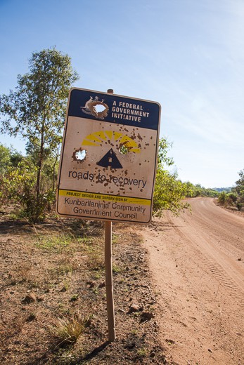 Leaving Kakadu national park and crossing the East Alligator River into Arnhem Land the scenery changes like a slide in an old projector. Meandering down a red and dusty road, a lonesome sign stands fatigued with irony.