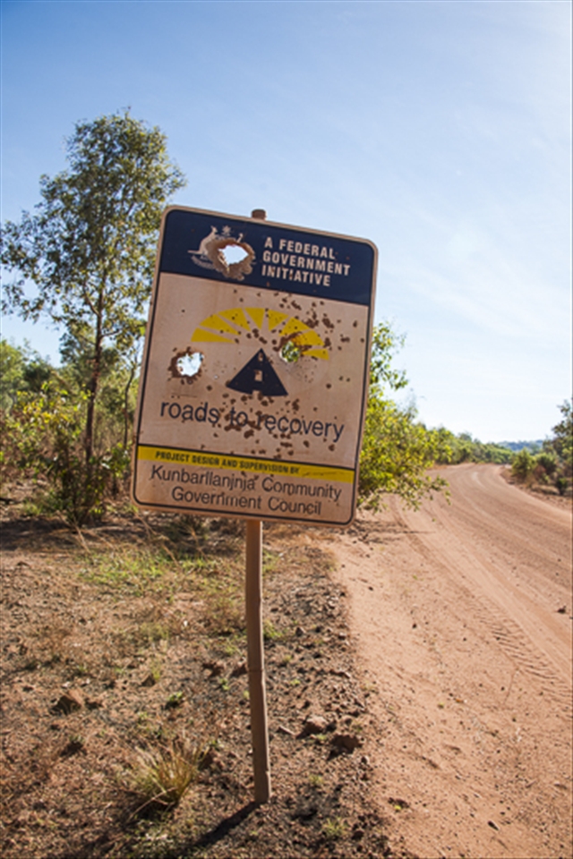 Leaving Kakadu national park and crossing the East Alligator River into Arnhem Land the scenery changes like a slide in an old projector. Meandering down a red and dusty road, a lonesome sign stands fatigued with irony.