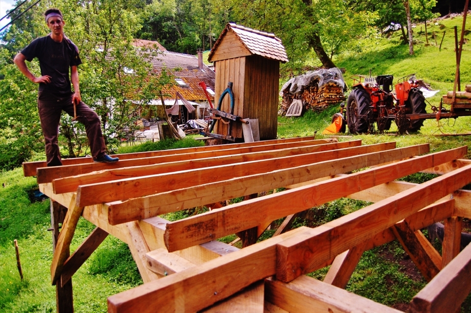Till works on a new project for the farm. The dance floor was built using wood from the field and will host a number of people for an upcoming party. On this farm in rural France visitors can come and stay for as long as they want,  on the condition that they help with daily functions. There are caravans located along the property along with several rooms within the farmhouse and the area is decorated with projects and artwork done by past inhabitants. Till has lived here for 4 years and remarks that it's only a pit-stop before he reaches Morocco.  