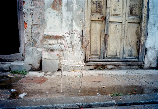 An old chair from decades past, sits abandoned on a desolate street in OldHavana