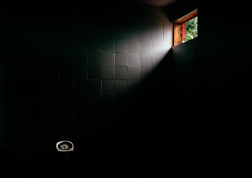 A small window casts some light on a weight scale in a hospital.