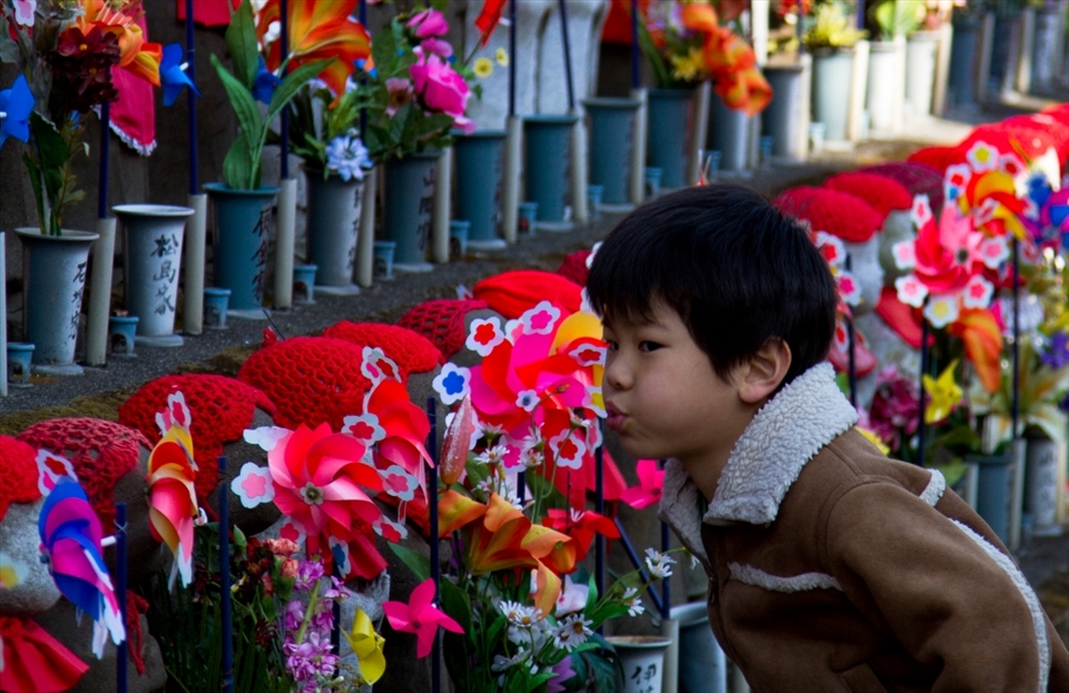A young boy visiting the Jizō Statues at Zojo-Ji Temple in Tokyo, who take care of the souls of unborn children and those who lost their life at a young age.