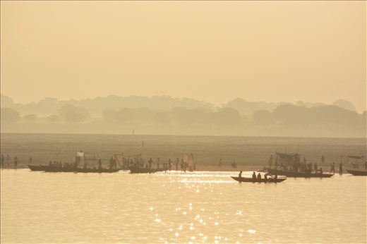 People hustle along the banks of the Ganges river in the early morning light.