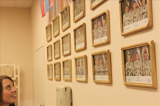 A girl watches closely towards a wall full of astronaut crew photographs in Baikonur Cosmodrome.