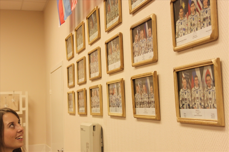 A girl watches closely towards a wall full of astronaut crew photographs in Baikonur Cosmodrome.
