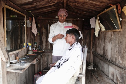 Rustic charm meets a brand new hair style as this barber grooms his subject with the precision of a surgeon. Huts like this are a common place for barbers and often a community of five or six barbers huts can be seen, with all the barbers sharing banter and trade between them.