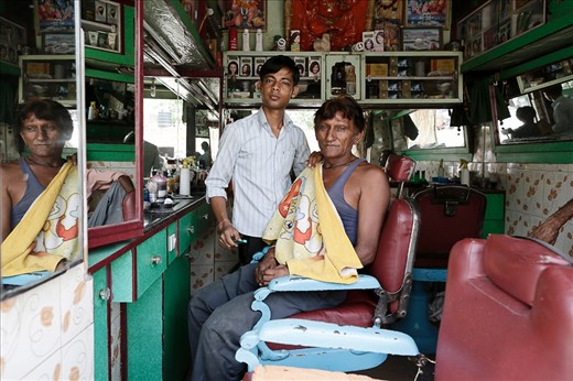 A young barber freshly shaves a wiser yet trusting customer as the medley of mirrors battle for reflections. Young barbers are common in India and the trade is seen as a sociable and respectable position among India's classes.