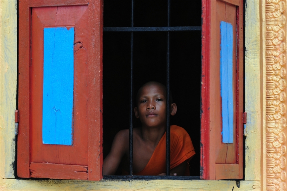 A young monk stares out the window of a temple oblivious. I held up my camera toask permission for a photo. There was absolutley no reaction, as if he was entranced. So I took a few photos and left him to his contemplation. Siem Reap - Cambodia