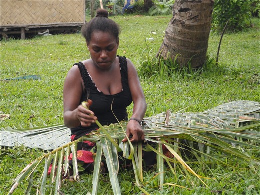 Vanuatu woman making coconut leaf basket used to carry goods