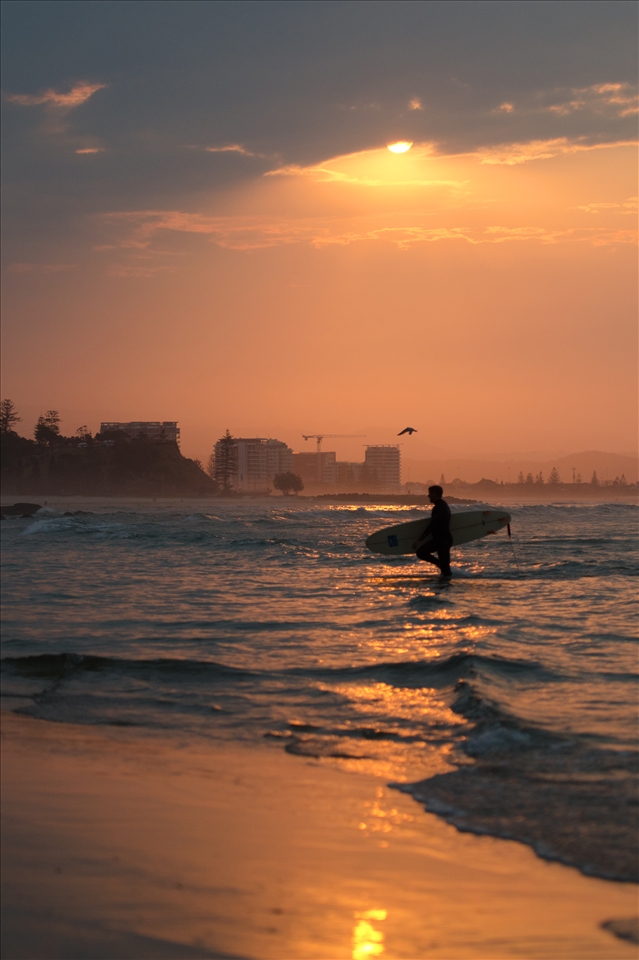 A Lone surfer is rewarded with a glimpse of brilliant sunset. 