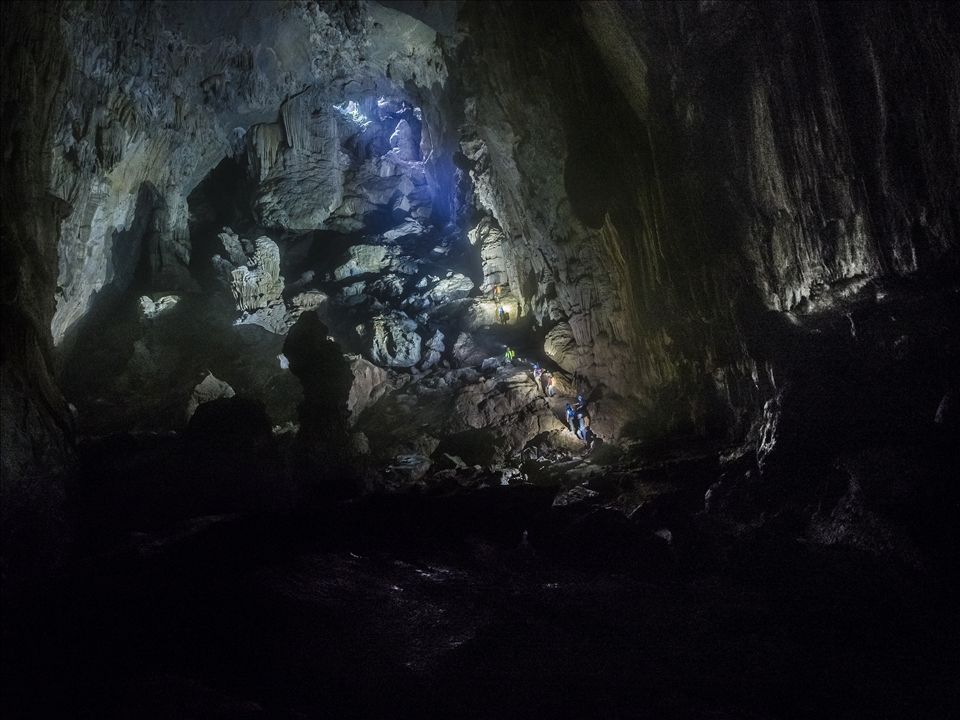 The gleaming rocks showcase a treasure chest of hidden natural wonder. The light from the entrance section is faint, itself being shrouded by boulders and forest. 