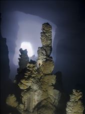 Our expedition leader Watson climbs a huge stalagmite to help photograph scale. From this particular vantage point, the 'Witches Hat' formation can be seen in the back ground, a unique silhouette, due to the glow from the first doline.: by being_lost, Views[404]