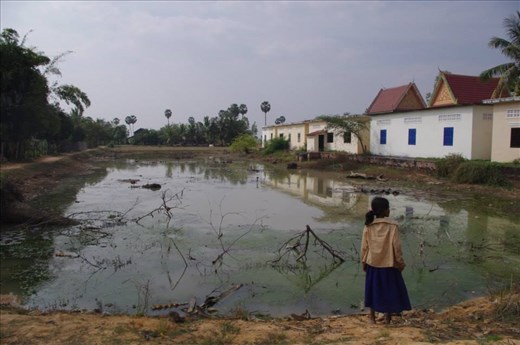A girl standing by a lake near her school