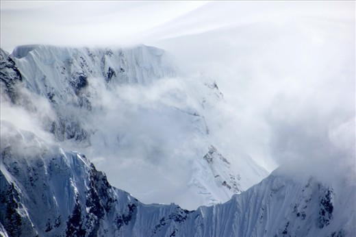Above the snow clouds and a world away from the storm swirling beneath the sun graces the tops of the glaciated peaks as seen from the Siula Pass  – Cordillera Huayhuash, Peru