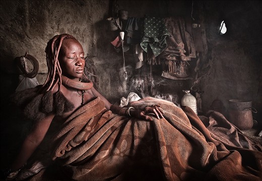 As soon as a Himba women wakes she begins her daily beauty ritual. The small fire that has smouldered all night inside her hut is then transformed into her mornings bath tub. Fragrant herbs are added to the fire as the women straddle themselves closely to the smoke and cover themselves with a large blanket, trapping the smoke, eliminating any unhygienic odours that may have accumulated over the previous 24 hours.