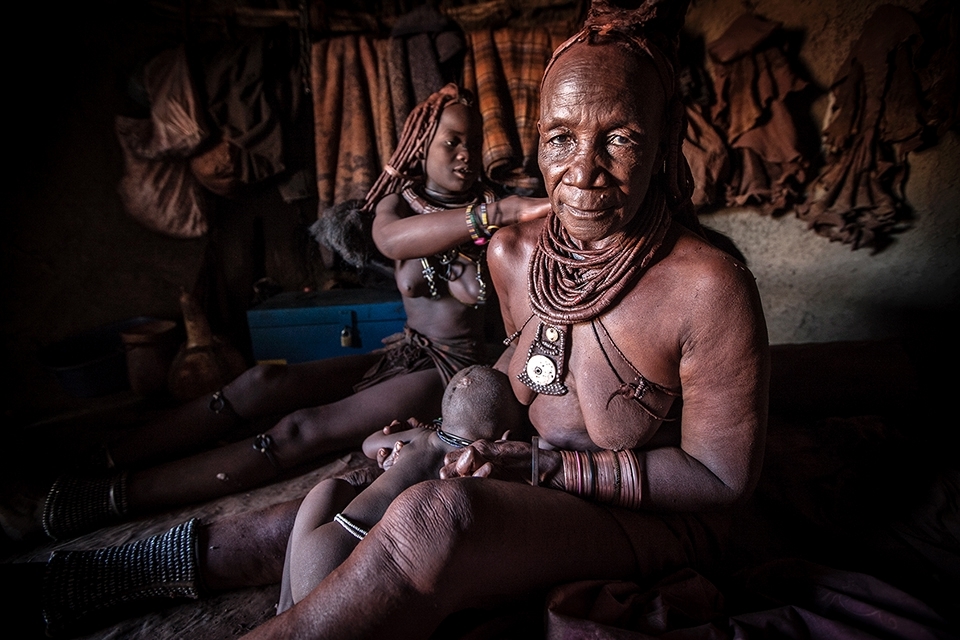 The Ochre is mixed with portions of thickened butter fat which is smeared all over the women's body to produce a bright red sheen. All of the females pitch in to help each other access areas that a single woman cannot. All of the Himba women share the work load in a village regardless of the task, their age or stature. 
