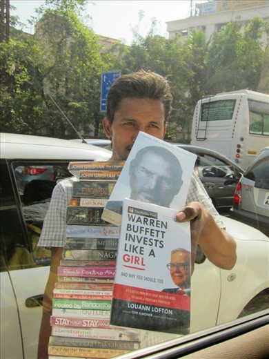 As cars carrying the newly rich come to stop for half a minute at a traffic light in Mumbai, a mob of young boys swiftly surround them- one offering to wash the windscreen, and the other selling water bottles with original labels but questionable water. But the most popular traffic light business is that of pirated books, which are sold for about a tenth of the market price. The sad irony however is that these “book boys” will remain illiterate throughout their lives.