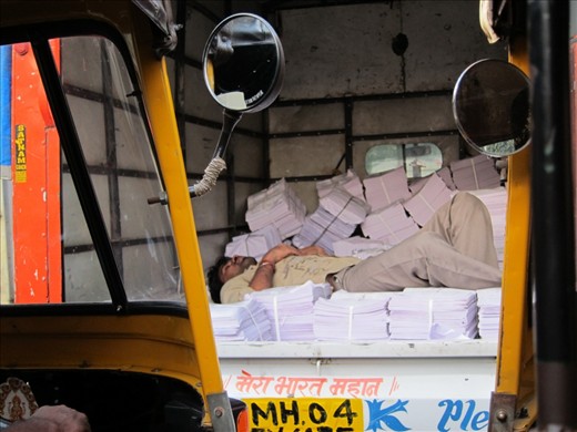 Rural migrants from nearby states flock to Mumbai in the hope of opportunity, despite all the efforts to stop them- including violence- from the conservative right-wing political parties. 20% of the hawkers’ earnings are collected as rent, and several ad-hoc bribes to local authorities are necessary to keep them on the streets. This immigrant worker, seen on a truck that says “Mera Bharat Mahan” (My India is great), was caught dozing in a traffic jam amidst the honking of “auto-rickshaws”.