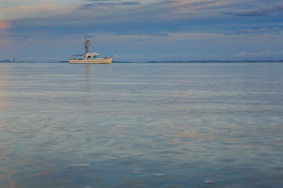 Was walking along the shore of Cornwallis  Beach New Zealand, during sunset and snap this boat alone in the sea and the sky makes a beautiful colour in the sea.