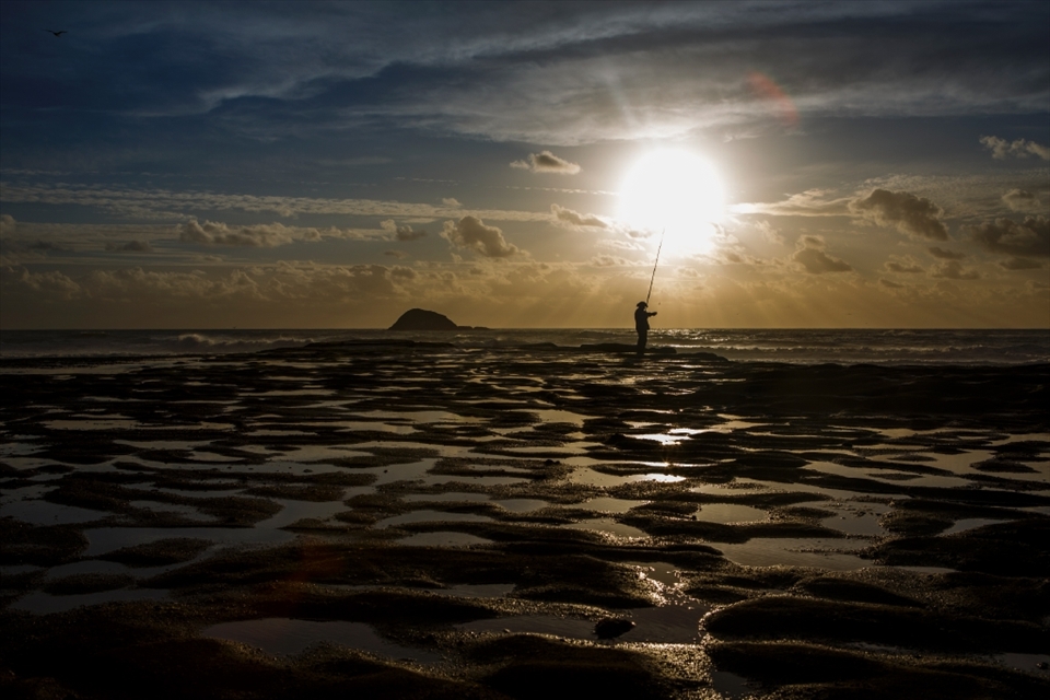 Snap this photo while a fisherman was catching a fish. Muriwai Beach, New Zealand