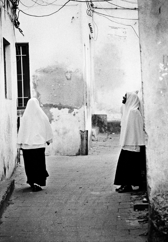 A Zanzibar schoolgirl is delighted by the antics of boys just behind the wall. Any one of them could one day be her husband. She is destined for an arranged marriage into which she will gladly enter to uphold her family's honour.