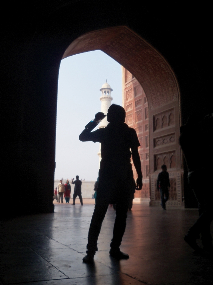 silhouette of man drinking water, standing between the gate.