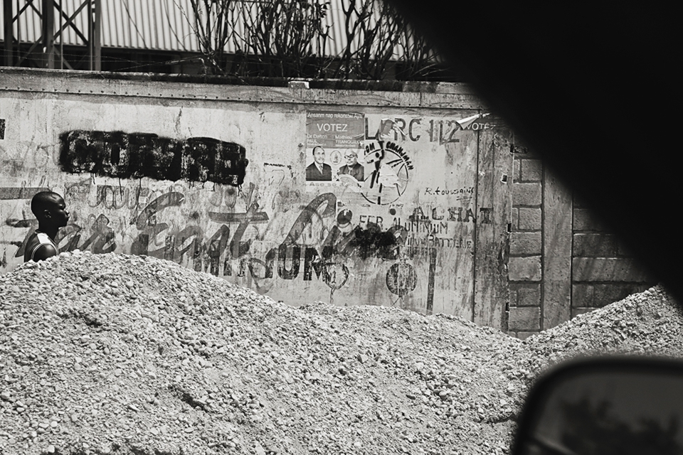 After the earthquake in Haiti, the rebuild was a long, slow process.  Roads were lined with construction material, garbage and rubble for months after the disaster. Here a man walks roadside barely visible over the piles.