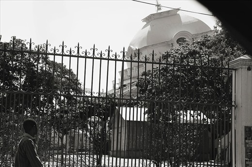 A Haitian man walks by the now leaning and heavily guarded Palais National.  For a year after the quake, government officials were still seen removing government materials out of the heavily damaged building.  