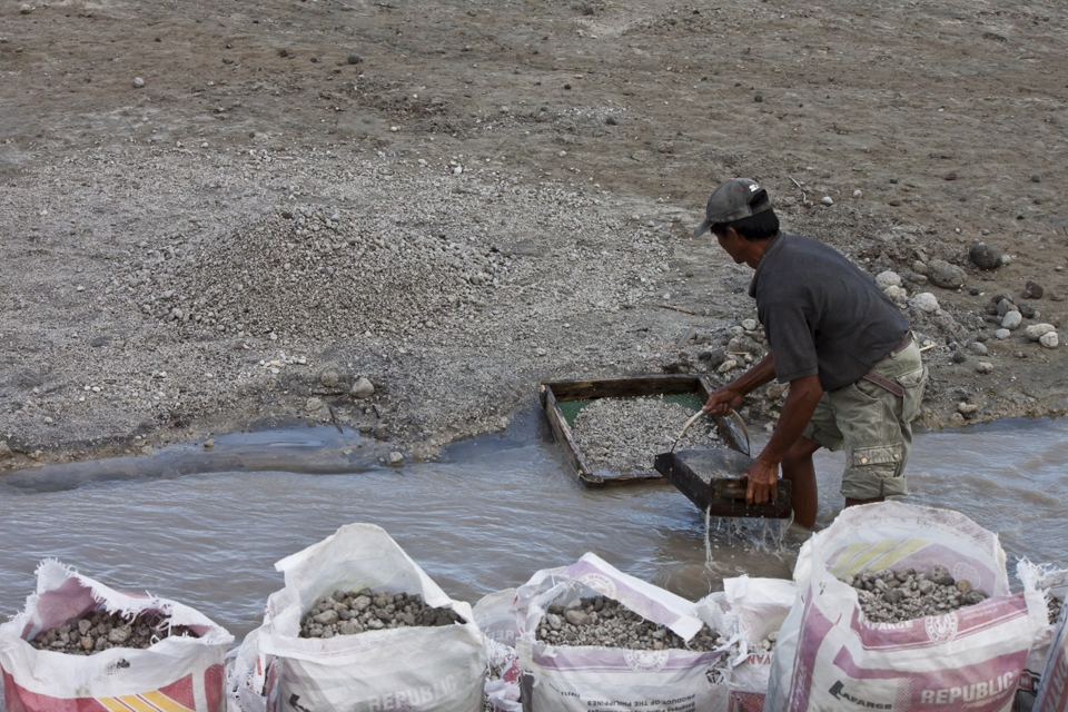 Iko, 52, the first miner in the family  gathering the stones from the river, which will be  filtered and sorted eventually according to their sizes.