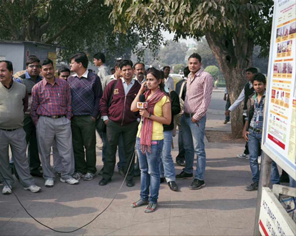 A group of men gather around a news reporter
