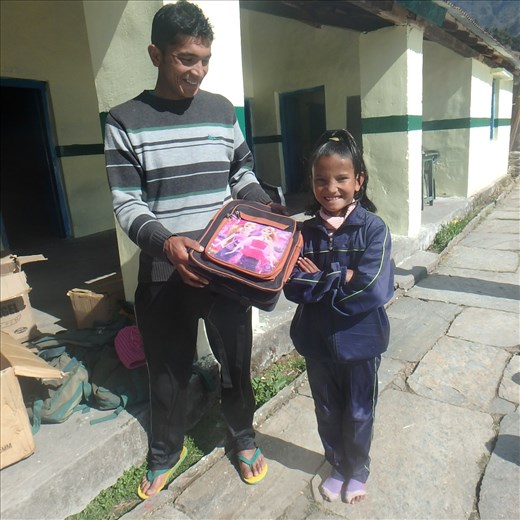 Praveen (community teacher at Jatoli) about to hand Munju her new school bag.
