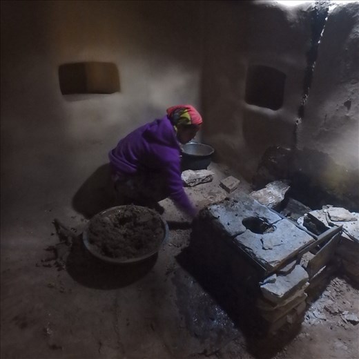 Dana is lovingly applying 'lal mart' or red clay. This rendering of the stove is practical by rounding off edges and aesthetically beautiful.